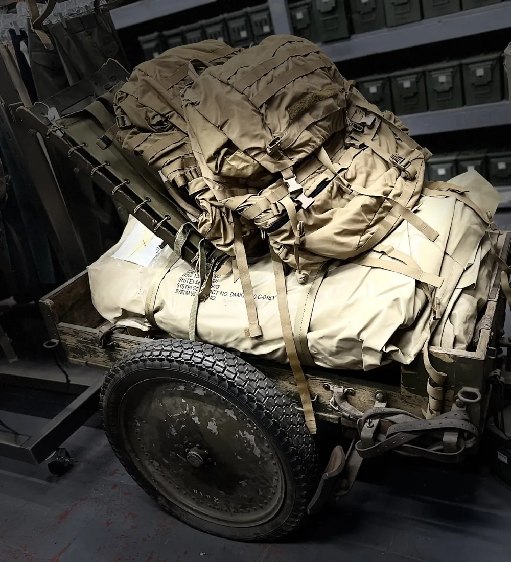 Military rucksacks and gear displayed on a vintage Army trailer
