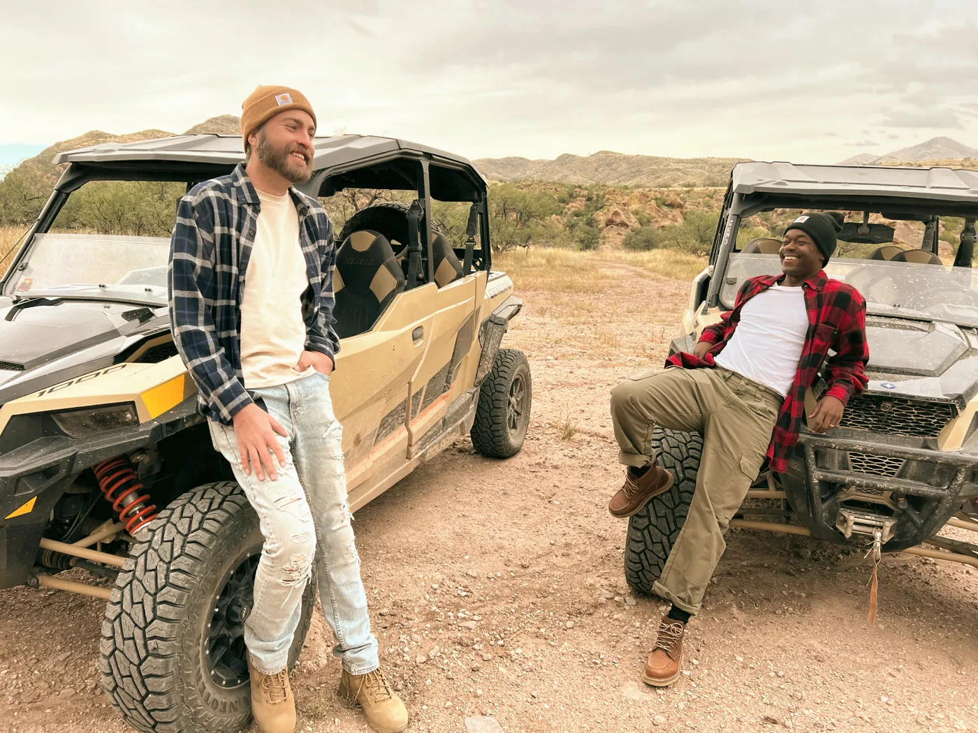 Two men in outdoor workwear with off-road vehicles in the Arizona desert